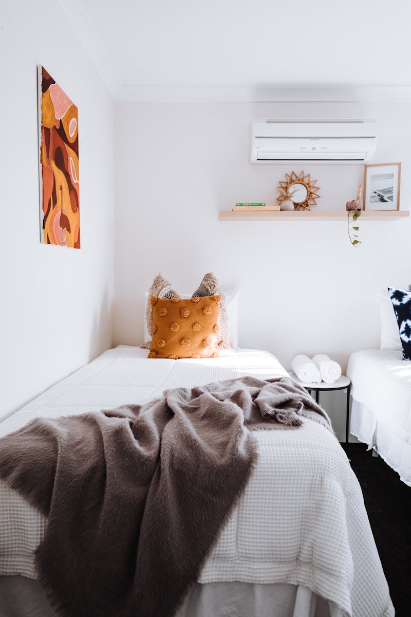 A minimalist bedroom featuring a single bed with soft textures, warm decor, and modern design.